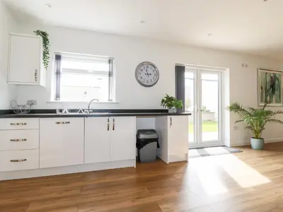 a kitchen with white cabinets and a clock on the wall at Penn-An-Vownder in Newquay