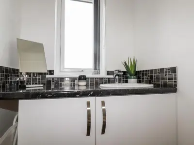 a white bathroom with a sink and a window at Penn-An-Vownder in Newquay