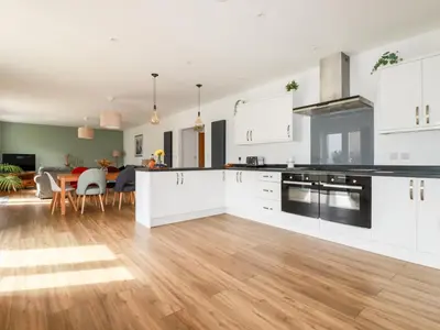 a kitchen with white cabinets and a dining room at Penn-An-Vownder in Newquay