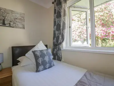 a bed with a pillow sitting next to a window at Watergate Bay in Liskeard