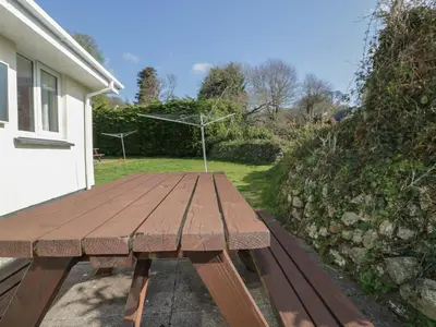 a wooden picnic table sitting outside of a house at Watergate Bay in Liskeard