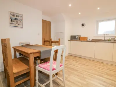 a kitchen and dining room with a wooden table and chairs at Lily Cottage in Camelford