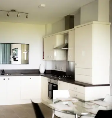 a kitchen with white cabinets and a glass table at Stunning Sea Views, luxury apartment beaches & restaurants are a short walk away in Newquay