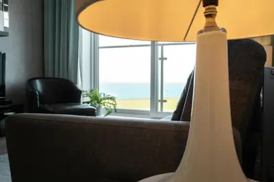 a lamp in a living room with a couch and a window at Stunning Sea Views, luxury apartment beaches & restaurants are a short walk away in Newquay