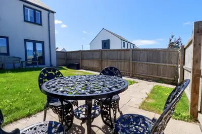 a table with four chairs and a table with a fence at The Sand Dunes in Crantock