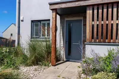 a house with a blue door and a fence at The Sand Dunes in Crantock