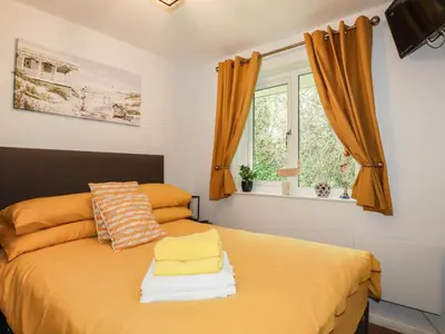a bedroom with a bed with yellow sheets and a window at Blue Sky Cottage in Liskeard