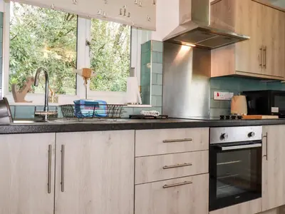 a kitchen with wooden cabinets and a sink and a window at Blue Sky Cottage in Liskeard
