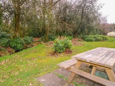 a wooden picnic table sitting in the grass at Blue Sky Cottage in Liskeard