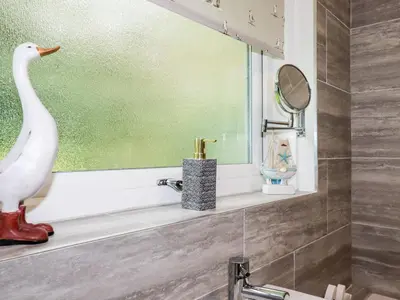 a bathroom with a swan on a shelf and a mirror at Blue Sky Cottage in Liskeard