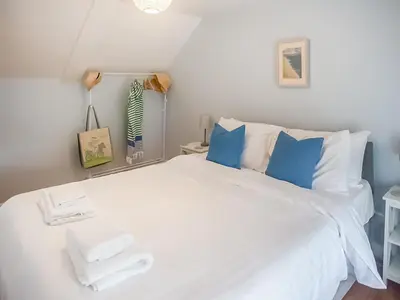 a bedroom with a large white bed with blue pillows at Little Trevarrack in Carbis Bay