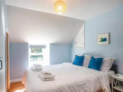 a bedroom with a white bed with blue pillows at Little Trevarrack in Carbis Bay