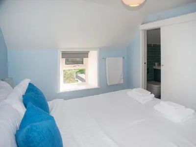 a white bed in a blue room with a window at Little Trevarrack in Carbis Bay