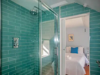 a blue tiled bathroom with a shower and a bed at Little Trevarrack in Carbis Bay