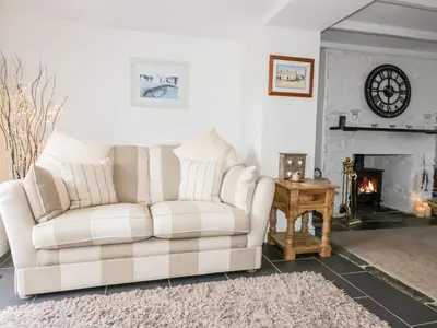 a living room with a white couch and a fireplace at Hawthorn Cottage in Bodmin