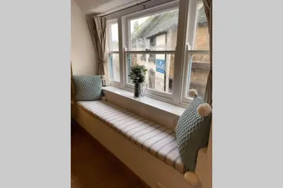 a bench in front of a window with a vase at The Nest - St Ives in St Ives
