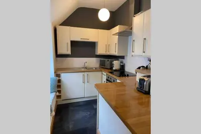 a kitchen with white cabinets and a wooden counter top at The Nest - St Ives in St Ives