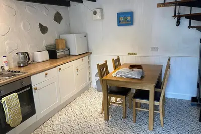 a kitchen with a wooden table and a table and chairs at Cottage in village of Mevagissey Cornwall Sleeps 4 in Mevagissey