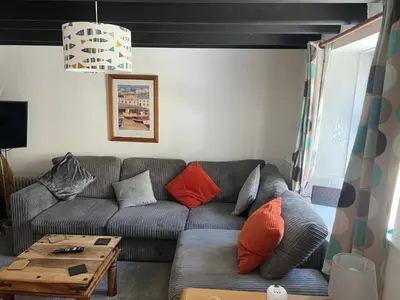 a living room with a gray couch with orange pillows at Cottage in village of Mevagissey Cornwall Sleeps 4 in Mevagissey