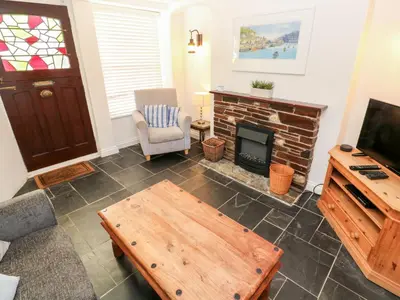 a living room with a table and a fireplace at Bay Tree Cottage in Looe