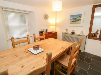 a dining room with a wooden table and chairs at Bay Tree Cottage in Looe