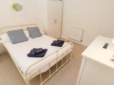 a bedroom with a bed with blue pillows on it at Bay Tree Cottage in Looe