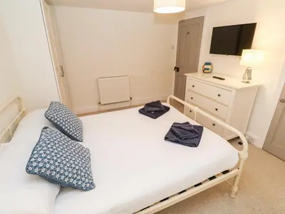 a small bedroom with a bed and a dresser at Bay Tree Cottage in Looe