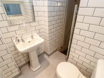 a white bathroom with a sink and a toilet at Bay Tree Cottage in Looe