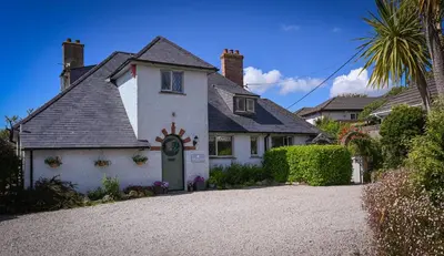 a white house with a clock on the side of it at Halwell Lodge in St Ives