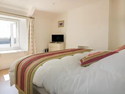 a white bedroom with a bed with a window at Puffin Cottage in Truro