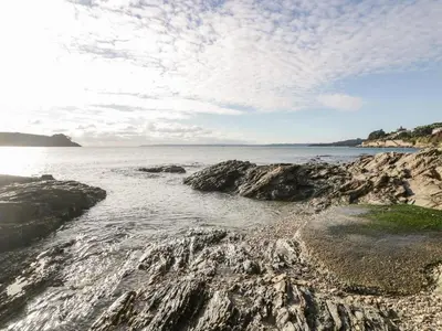 a beach with rocks in the water and a cloudy sky at Puffin Cottage in Truro
