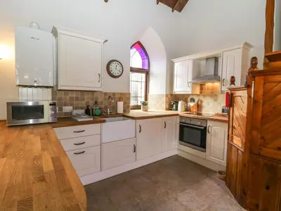 a kitchen with white cabinets and a clock on the wall at Frogwell Chapel in Callington