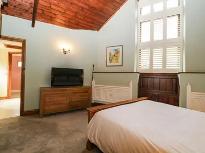 a bedroom with a bed and a flat screen tv at Frogwell Chapel in Callington