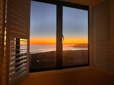 a window with a view of the ocean at sunset at Sea Sands in Penzance