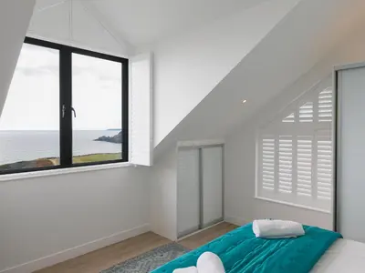 a bedroom with a bed and a large window at Sea Sands in Penzance