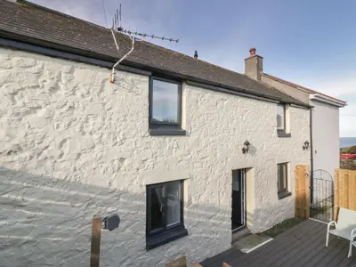 a white stone house with a deck at Rose Cottage in St Ives
