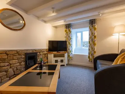 a living room with a fireplace and a tv at Rose Cottage in St Ives