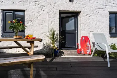 a patio with a table and a chair next to a door at Rose Cottage in St Ives