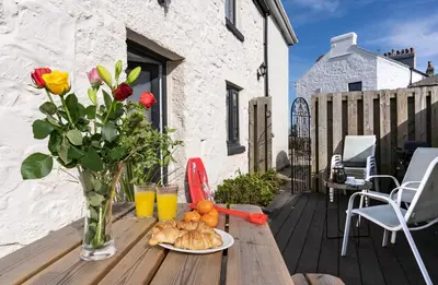 a table with a vase of flowers and a plate of food at Rose Cottage in St Ives