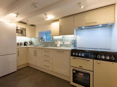 a kitchen with white cabinets and a stove top oven at Rose Cottage in St Ives