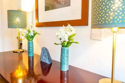 two vases with flowers on a table with two lamps at Falmouth Bay Holiday Apartments in Falmouth