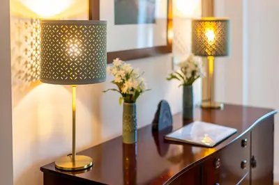 a desk with two lamps and flowers on it at Falmouth Bay Holiday Apartments in Falmouth