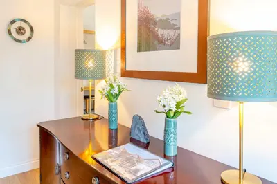 a desk with two lamps and flowers on it at Falmouth Bay Holiday Apartments in Falmouth