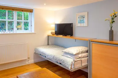 a room with a small bed with a television on it at Falmouth Bay Holiday Apartments in Falmouth