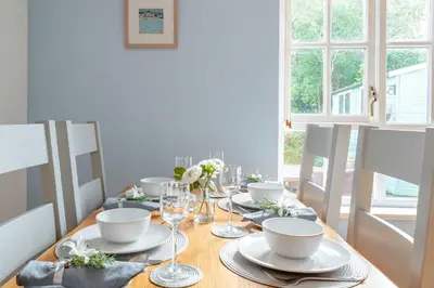 a dining room table with plates and wine glasses at Falmouth Bay Holiday Apartments in Falmouth
