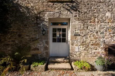a white door in a brick building with plants at Stable House in Redruth