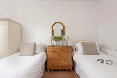 a bedroom with two beds and a dresser with a mirror at Stable House in Redruth