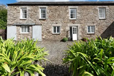 an old stone house with a garden in front of it at Stable House in Redruth