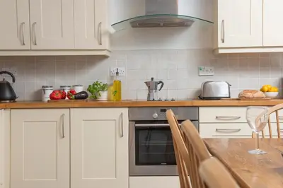 a kitchen with white cabinets and a counter top at Stable House in Redruth