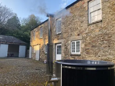 a brick building with smoke coming out of it at Stable House in Redruth